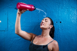 Woman pouring water from water bottle onto her face